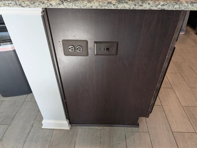 Dark wood cabinet with electrical outlets on front door, mounted on tile floor.